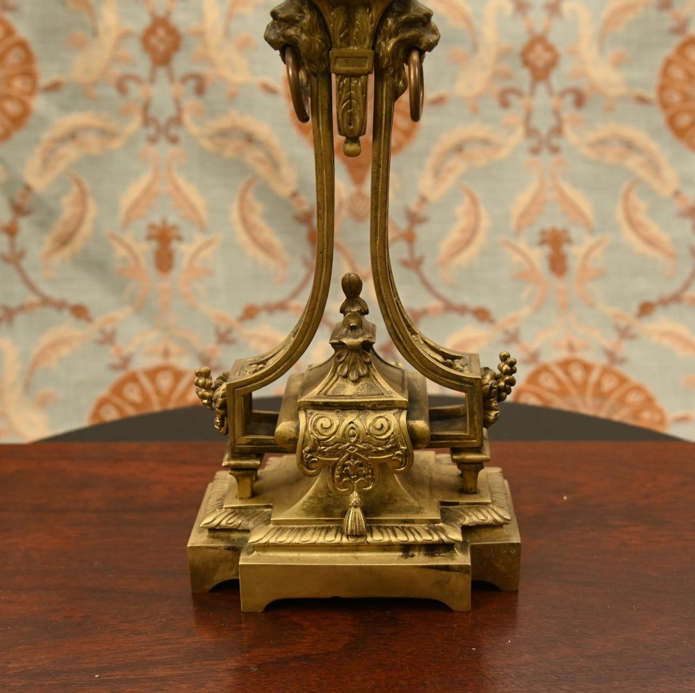A 19th-century Louis XVI style gilt bronze clock garniture set comprising a central ornate mantel clock flanked by two matching five-light candelabras. View V