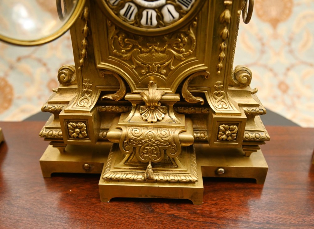 A 19th-century Louis XVI style gilt bronze clock garniture set comprising a central ornate mantel clock flanked by two matching five-light candelabras. View VII