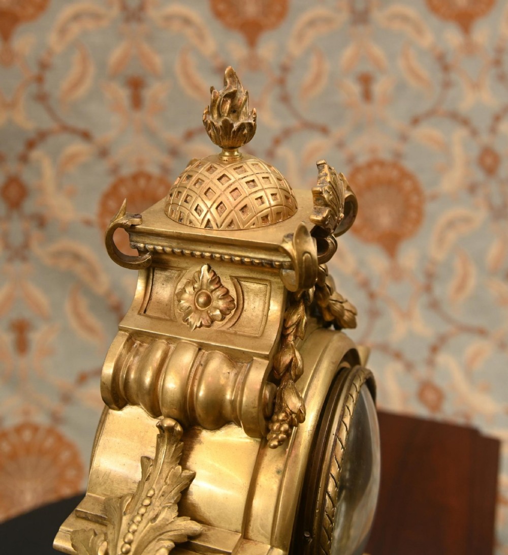 A 19th-century Louis XVI style gilt bronze clock garniture set comprising a central ornate mantel clock flanked by two matching five-light candelabras. View XIII