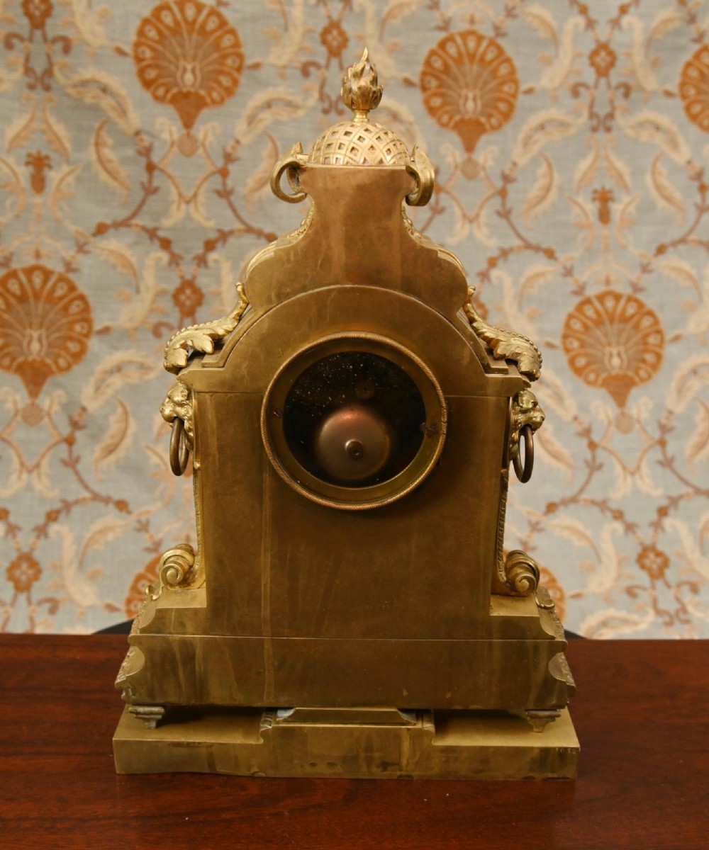 A 19th-century Louis XVI style gilt bronze clock garniture set comprising a central ornate mantel clock flanked by two matching five-light candelabras. View XIV