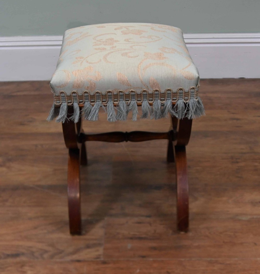 A Regency style mahogany stool featuring curved x-frame legs, a central turned stretcher, and a pale blue patterned damask upholstered seat finished with grey fringe trim. View III