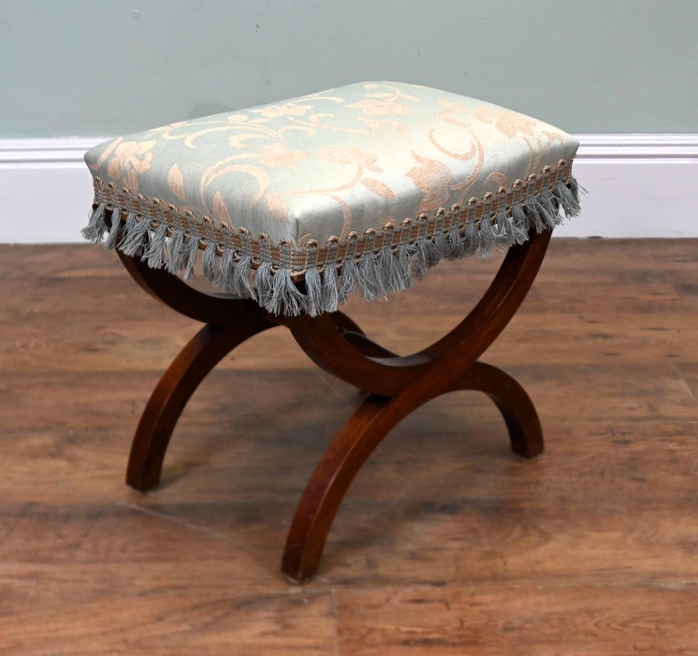 A Regency style mahogany stool featuring curved x-frame legs, a central turned stretcher, and a pale blue patterned damask upholstered seat finished with grey fringe trim. View IV