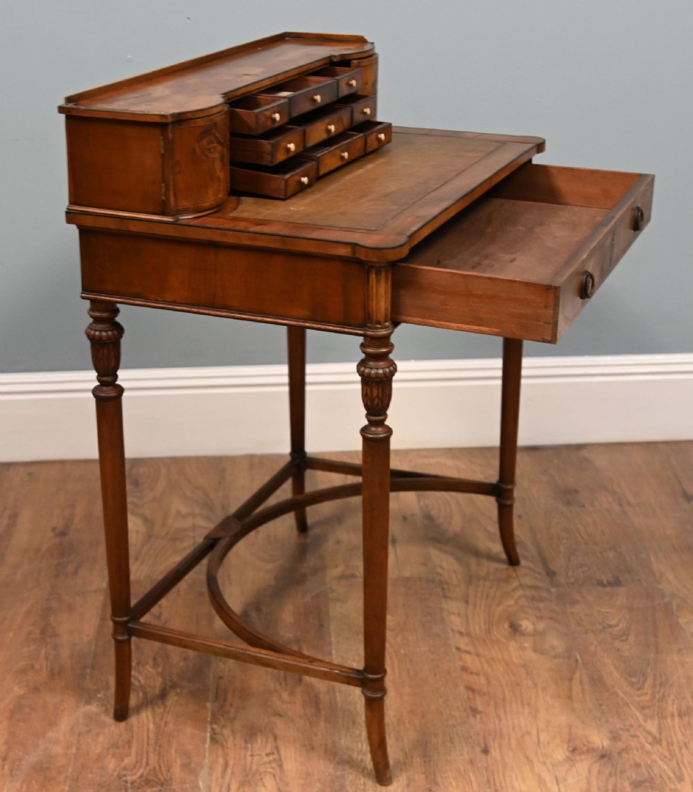 A Regency Revival mahogany ladies writing desk featuring a leather-lined writing surface, elevated drawer superstructure, turned reeded legs, and a curved stretcher. View II