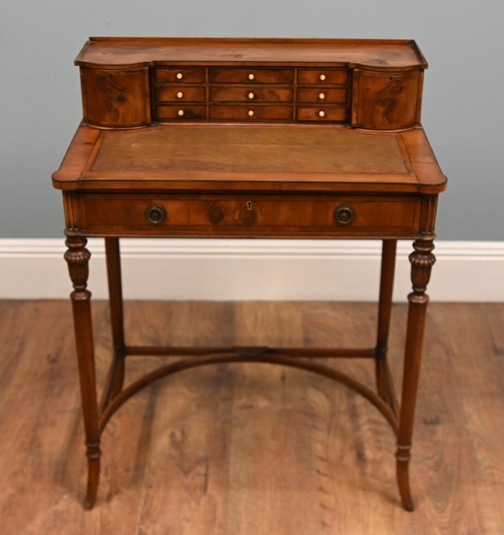 A Regency Revival mahogany ladies writing desk featuring a leather-lined writing surface, elevated drawer superstructure, turned reeded legs, and a curved stretcher. View VIII