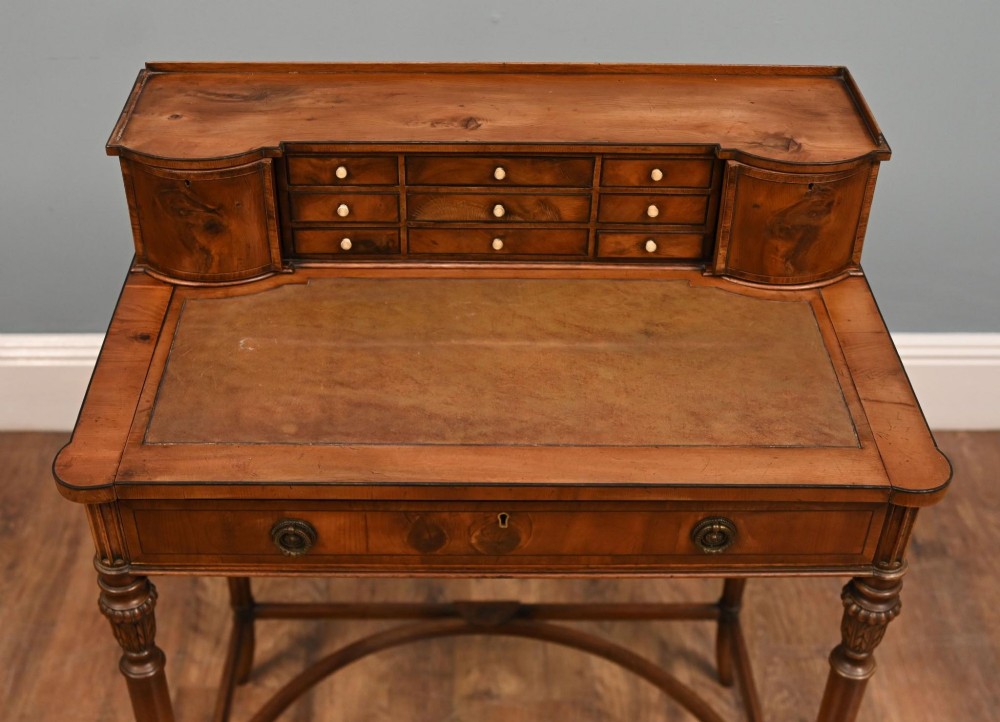 A Regency Revival mahogany ladies writing desk featuring a leather-lined writing surface, elevated drawer superstructure, turned reeded legs, and a curved stretcher. View IX