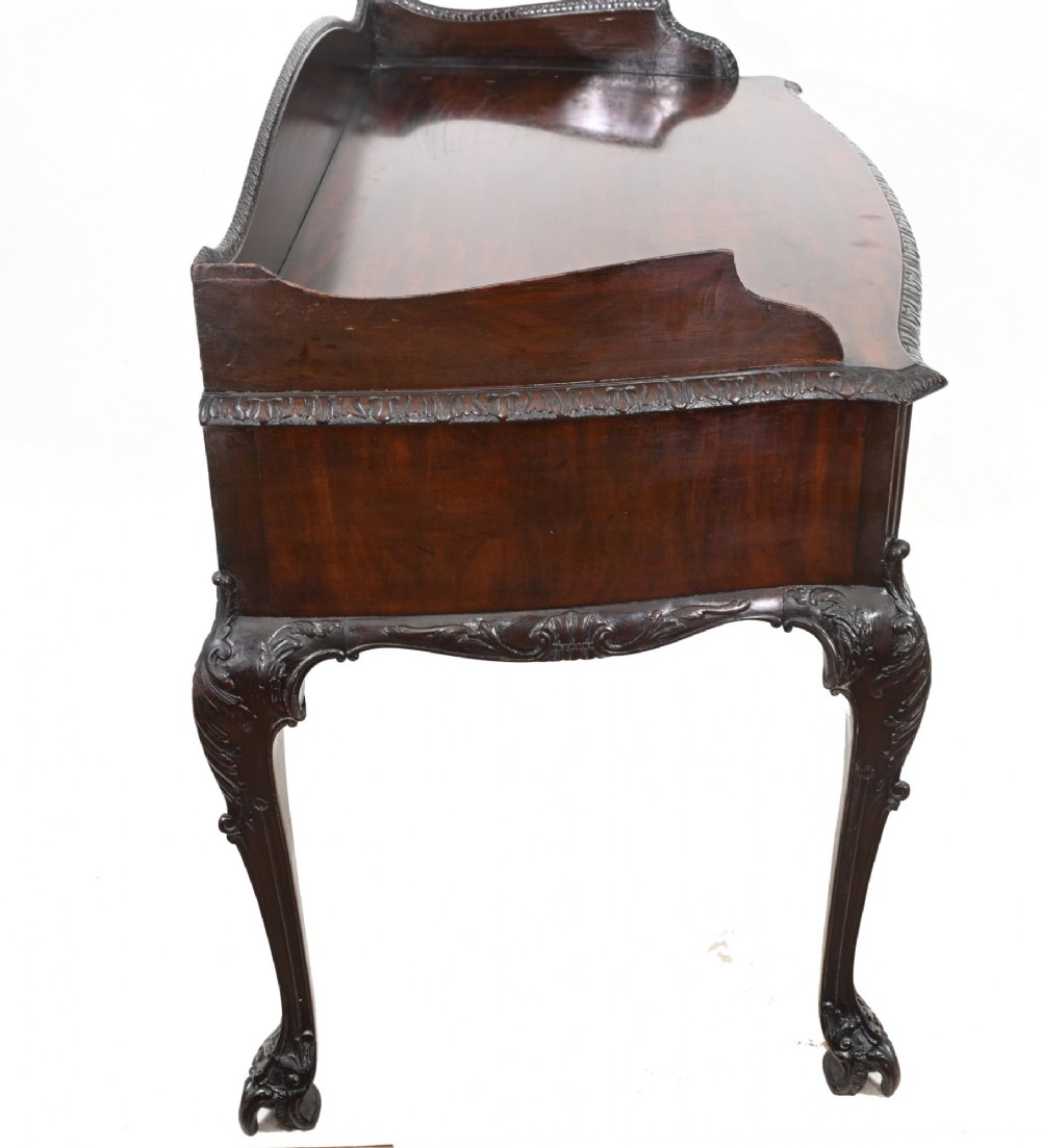 A dark mahogany Victorian console table featuring three drawers with decorative brass handles, carved cabriole legs, and a low gallery back. View IV