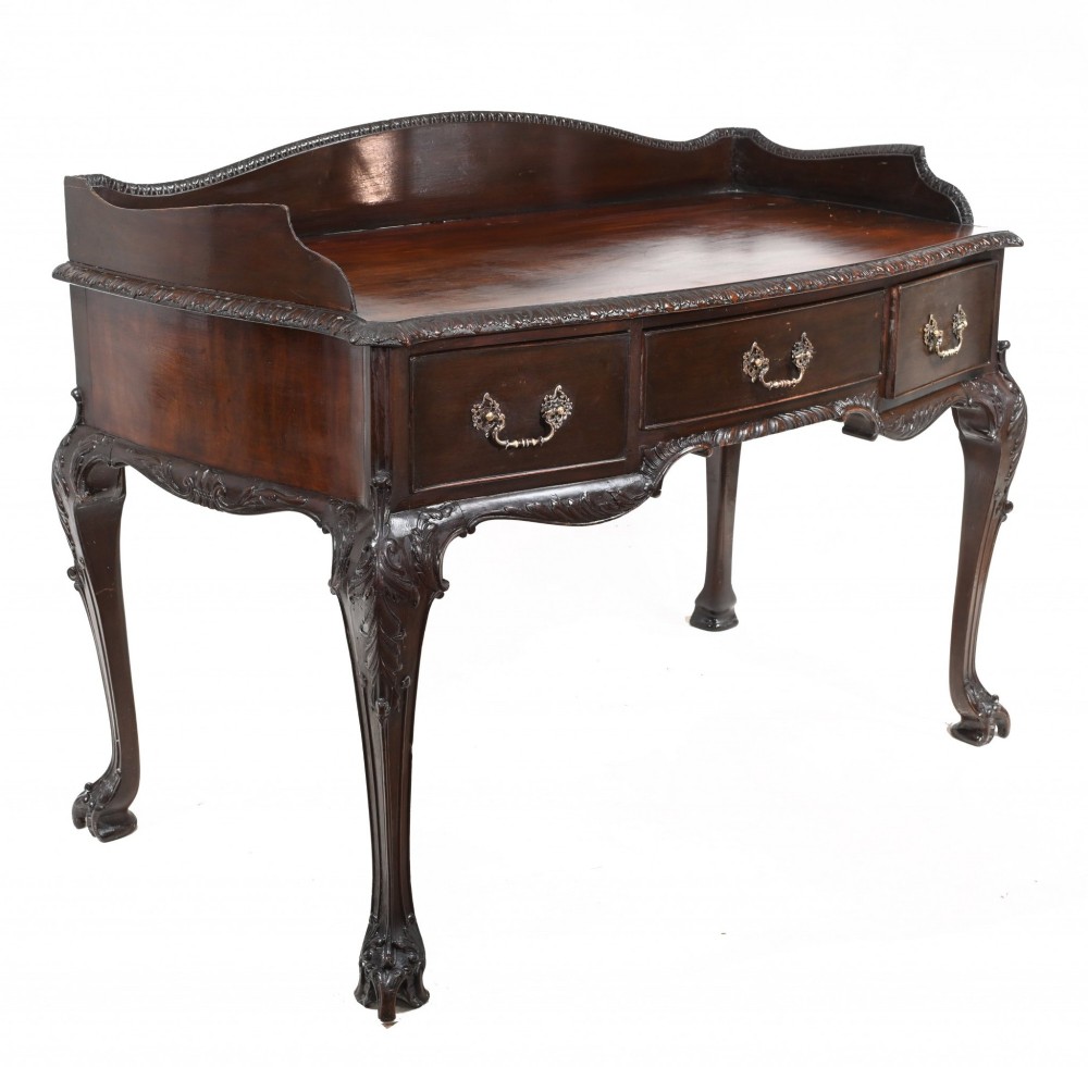 A dark mahogany Victorian console table featuring three drawers with decorative brass handles, carved cabriole legs, and a low gallery back. View VII