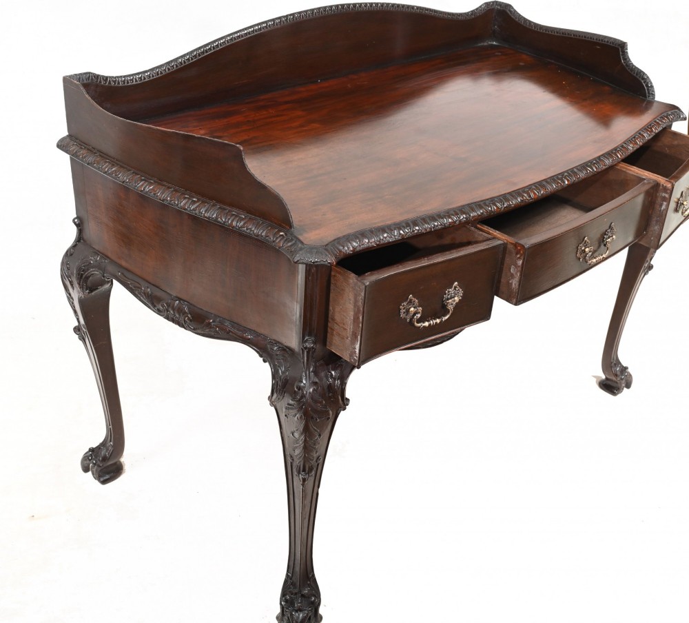 A dark mahogany Victorian console table featuring three drawers with decorative brass handles, carved cabriole legs, and a low gallery back. View IX