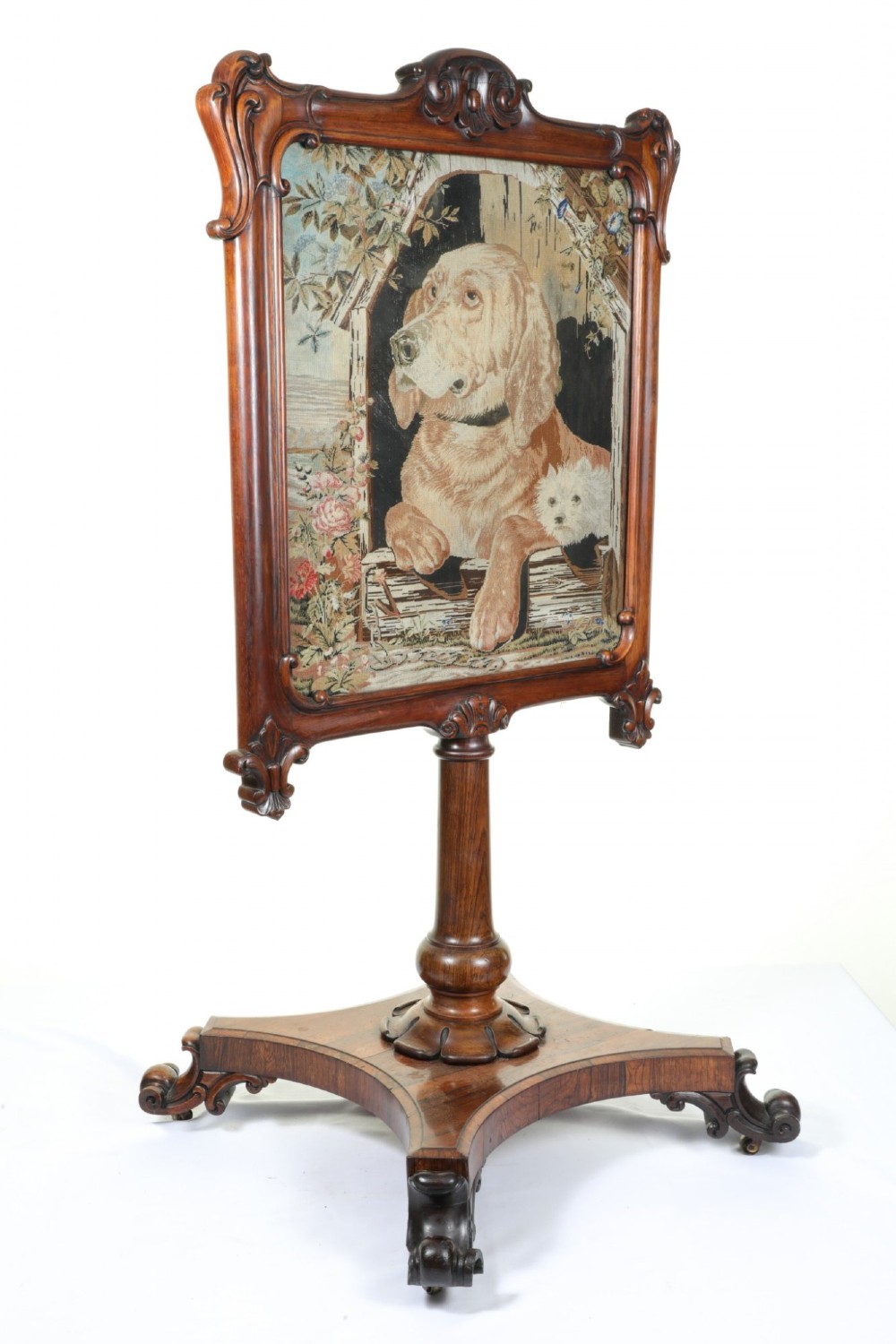 A Victorian carved mahogany fire screen featuring a needlepoint tapestry panel depicting a large hound and a small terrier inside a wooden kennel. View IV