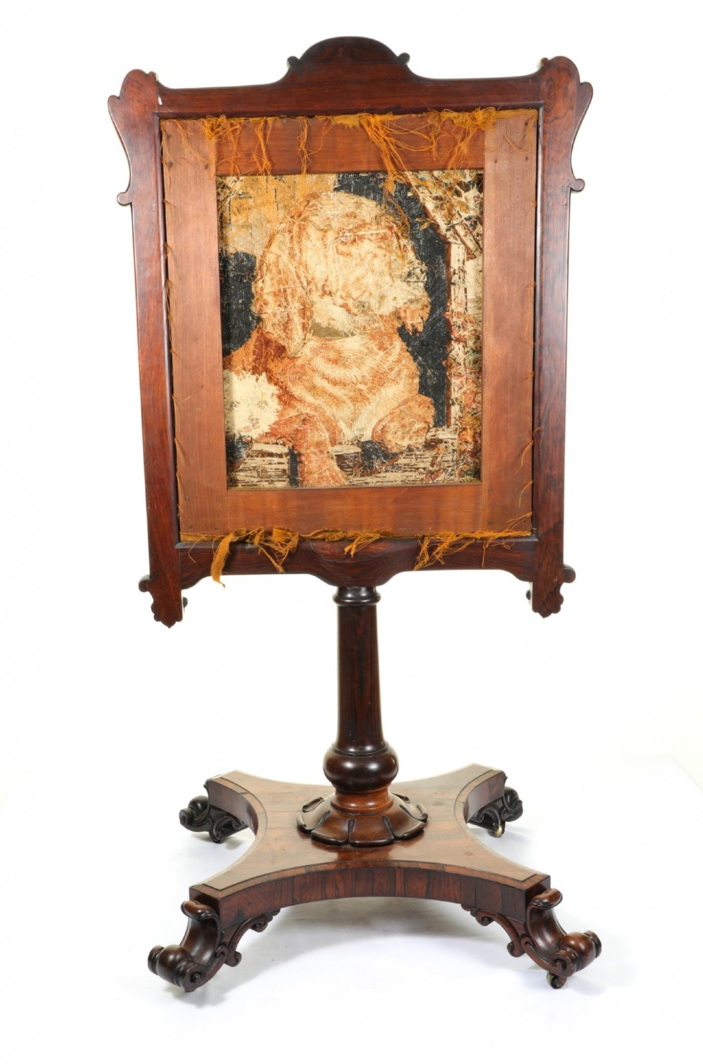A Victorian carved mahogany fire screen featuring a needlepoint tapestry panel depicting a large hound and a small terrier inside a wooden kennel. View VI