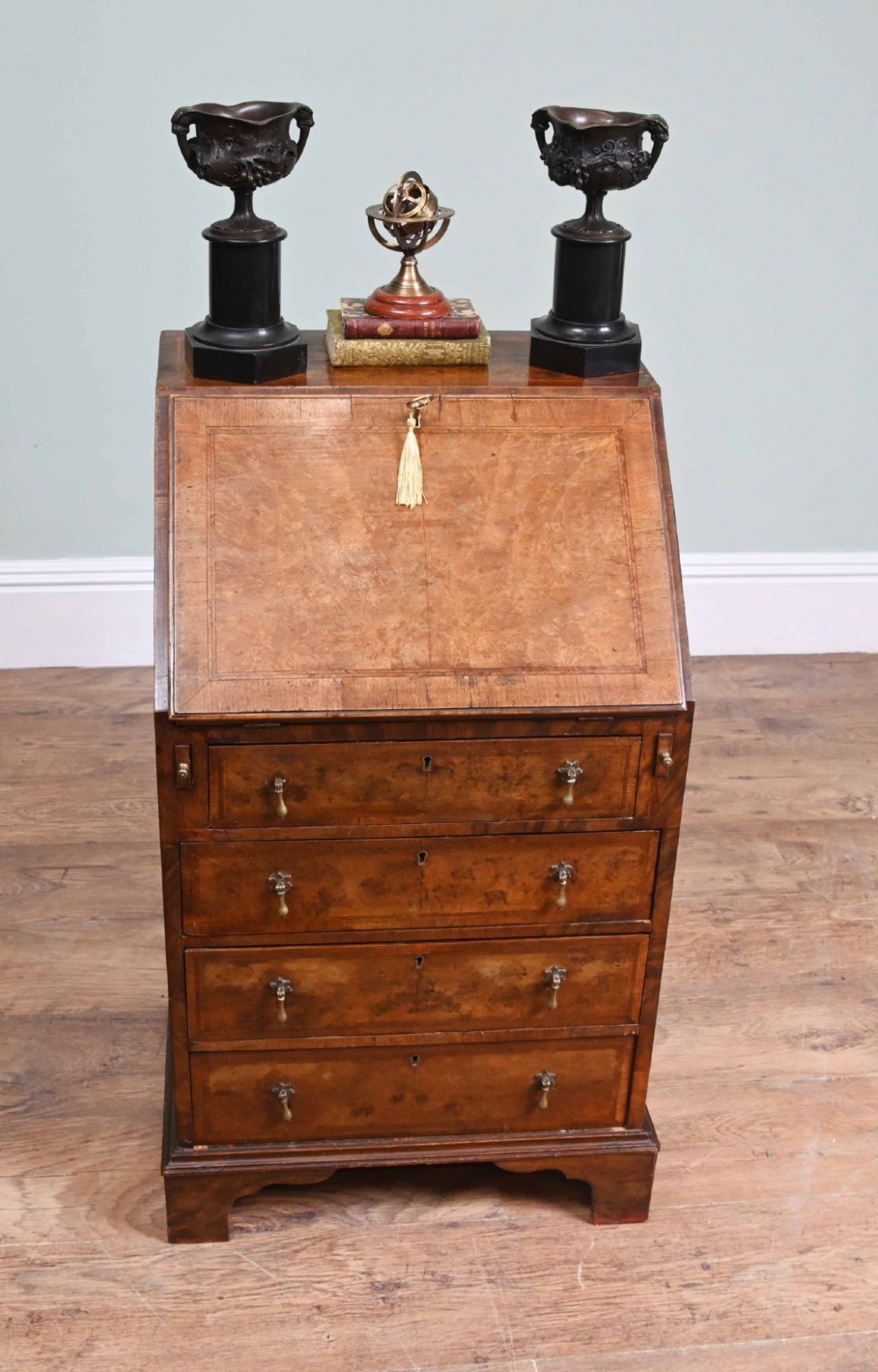 A late Victorian walnut slant-front bureau desk with four drawers and brass teardrop handles.