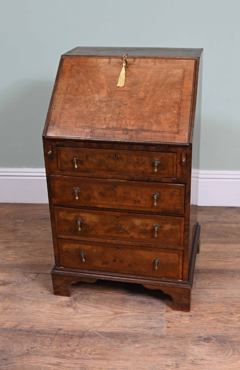 A late Victorian walnut slant-front bureau desk with four drawers and brass teardrop handles. View IX