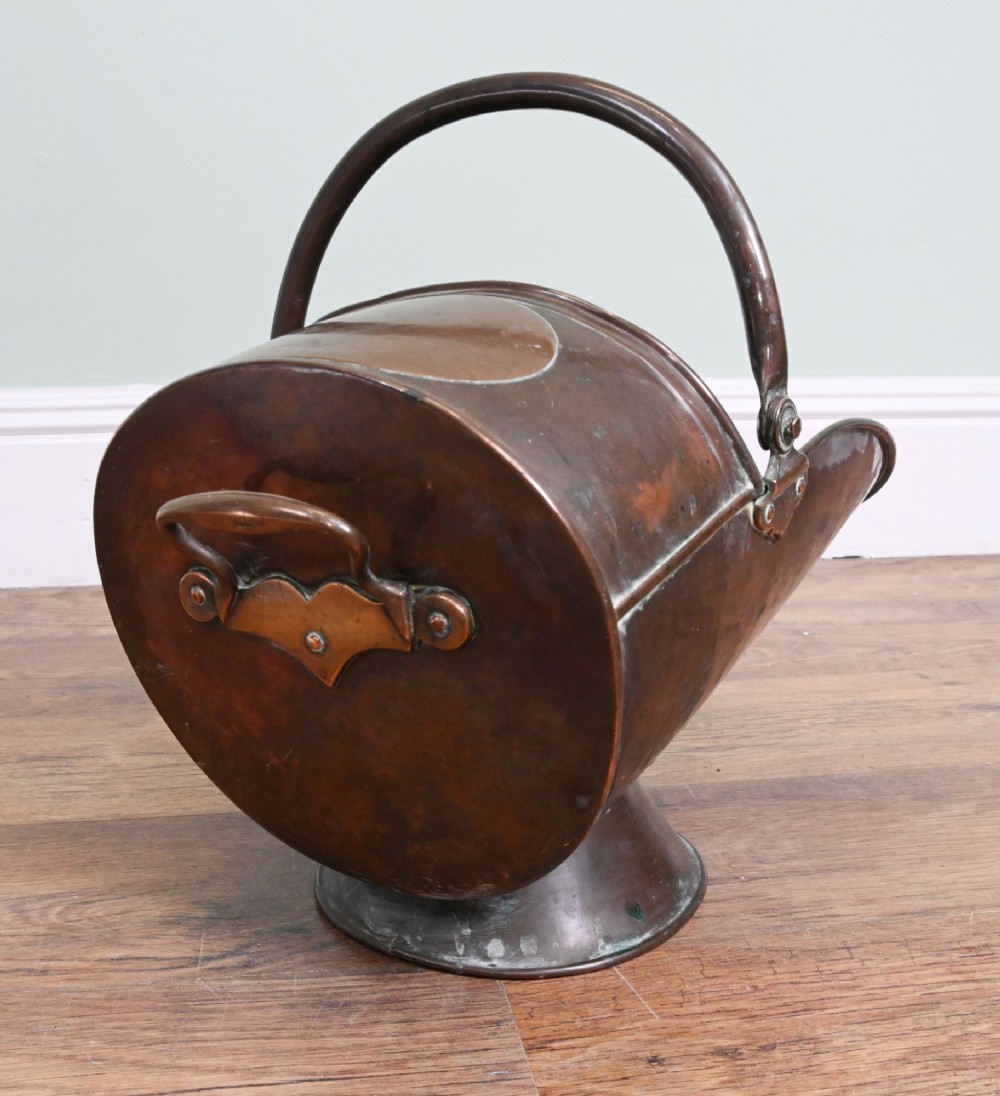 A Victorian copper helmet-shaped coal scuttle featuring a flared pedestal base and an arched swing handle. View II