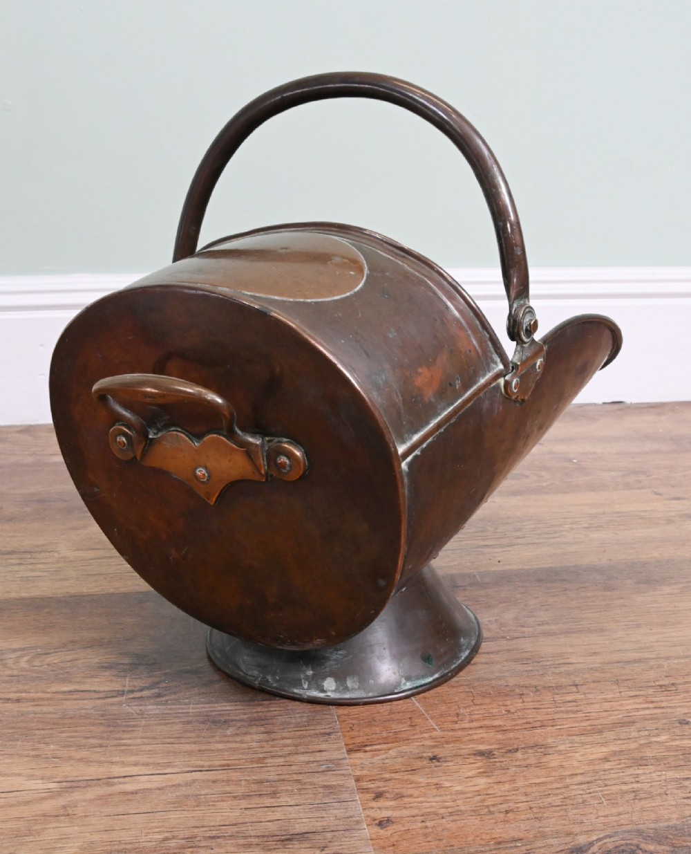A Victorian copper helmet-shaped coal scuttle featuring a flared pedestal base and an arched swing handle. View III