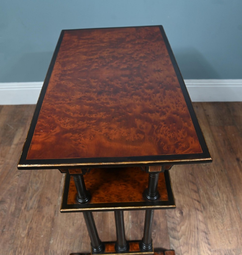 A late Victorian two-tier dumb waiter with warm amboyna wood surfaces, ebonised turned column supports, and splayed legs on castors. View VIII