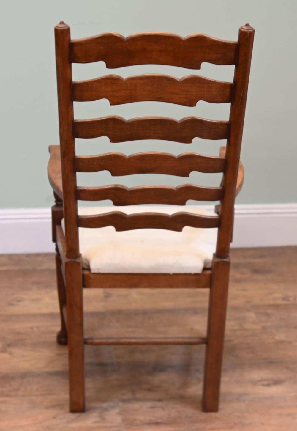 A set of four Edwardian oak ladderback dining chairs featuring two armchairs and two side chairs with turned legs and cream fabric seats. View II