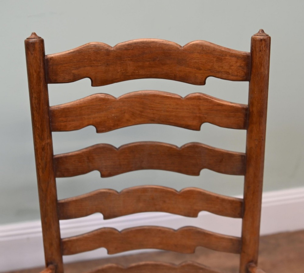 A set of four Edwardian oak ladderback dining chairs featuring two armchairs and two side chairs with turned legs and cream fabric seats. View V