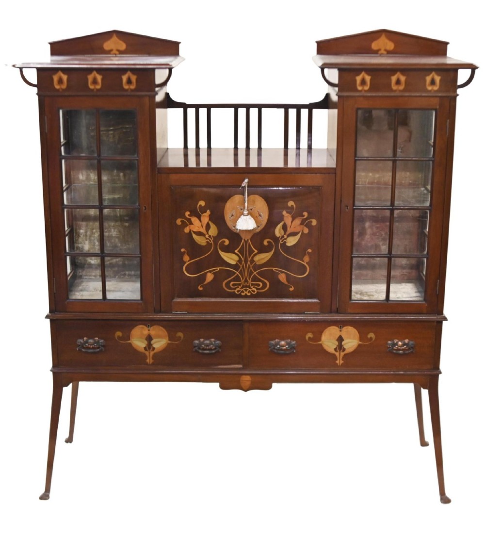 An Edwardian Art Nouveau dark mahogany drinks cabinet featuring stylised botanical marquetry inlays, twin glazed side doors, two lower drawers, and slender splayed legs.