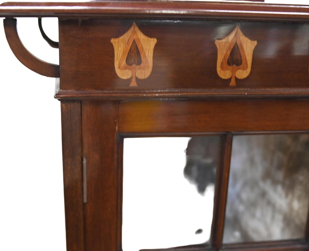 An Edwardian Art Nouveau dark mahogany drinks cabinet featuring stylised botanical marquetry inlays, twin glazed side doors, two lower drawers, and slender splayed legs. View IV