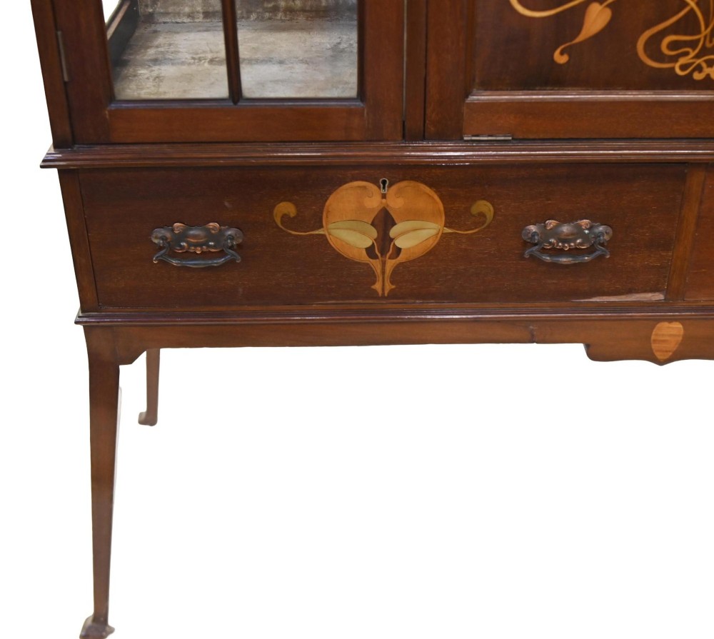 An Edwardian Art Nouveau dark mahogany drinks cabinet featuring stylised botanical marquetry inlays, twin glazed side doors, two lower drawers, and slender splayed legs. View IX