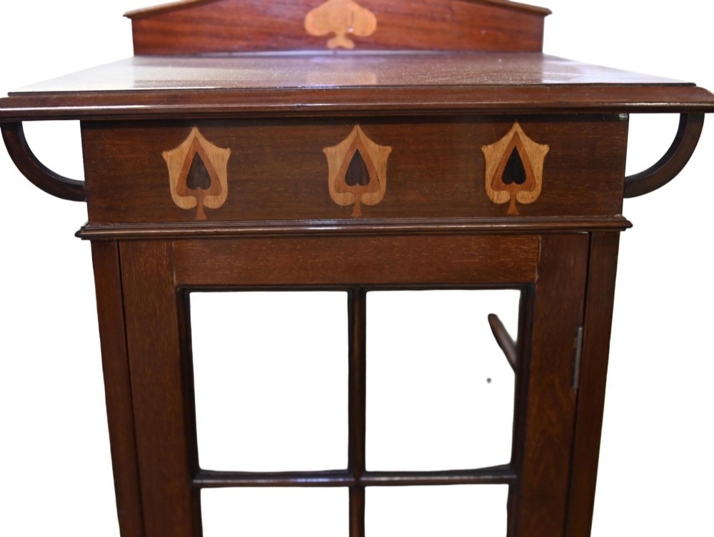 An Edwardian Art Nouveau dark mahogany drinks cabinet featuring stylised botanical marquetry inlays, twin glazed side doors, two lower drawers, and slender splayed legs. View X