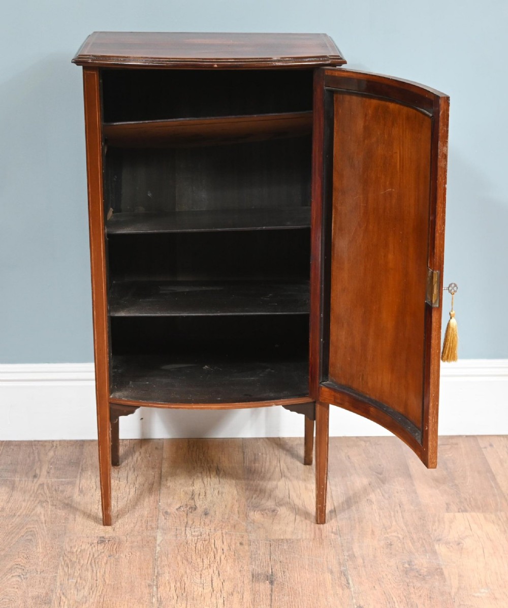 A late Victorian bow-fronted mahogany side cabinet with delicate boxwood line inlay, a single door with key, and slender square tapered legs. View IV