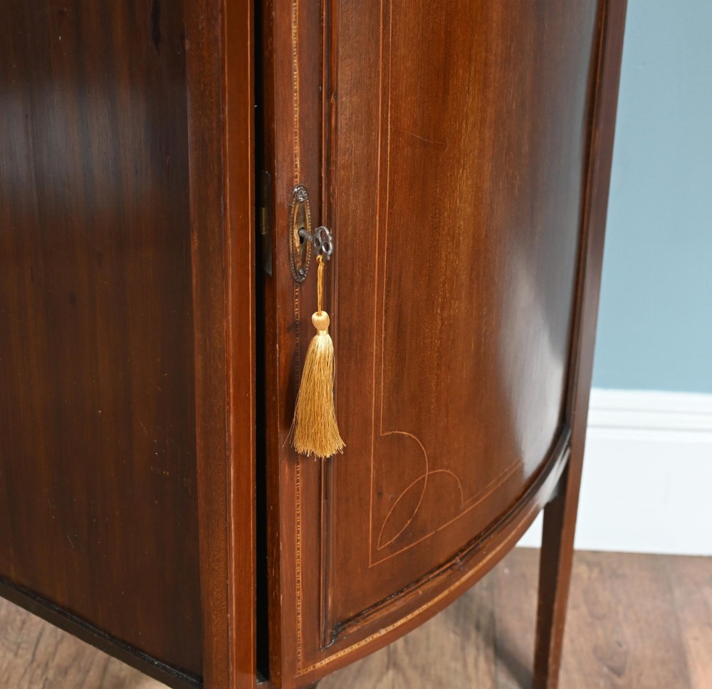 A late Victorian bow-fronted mahogany side cabinet with delicate boxwood line inlay, a single door with key, and slender square tapered legs. View VIII