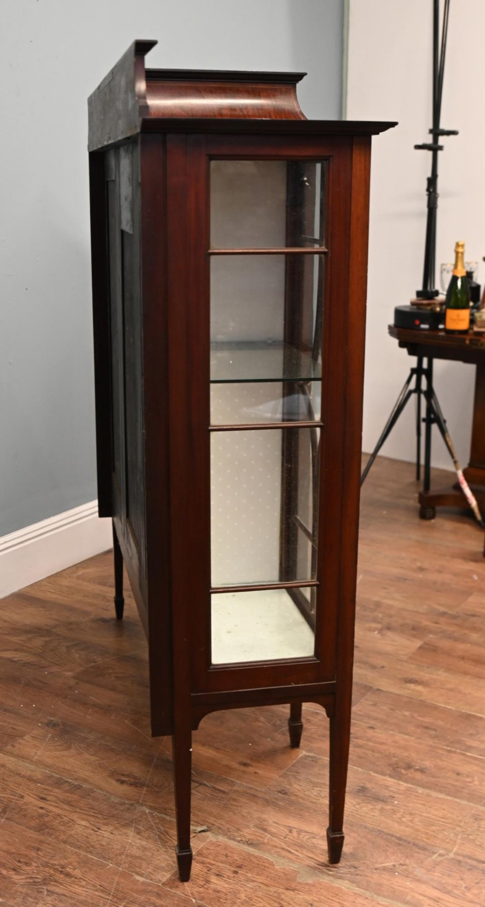 An Edwardian inlaid mahogany display cabinet featuring astragal glazed side doors, a central wooden cupboard with oval marquetry, and slender square tapered legs. View III