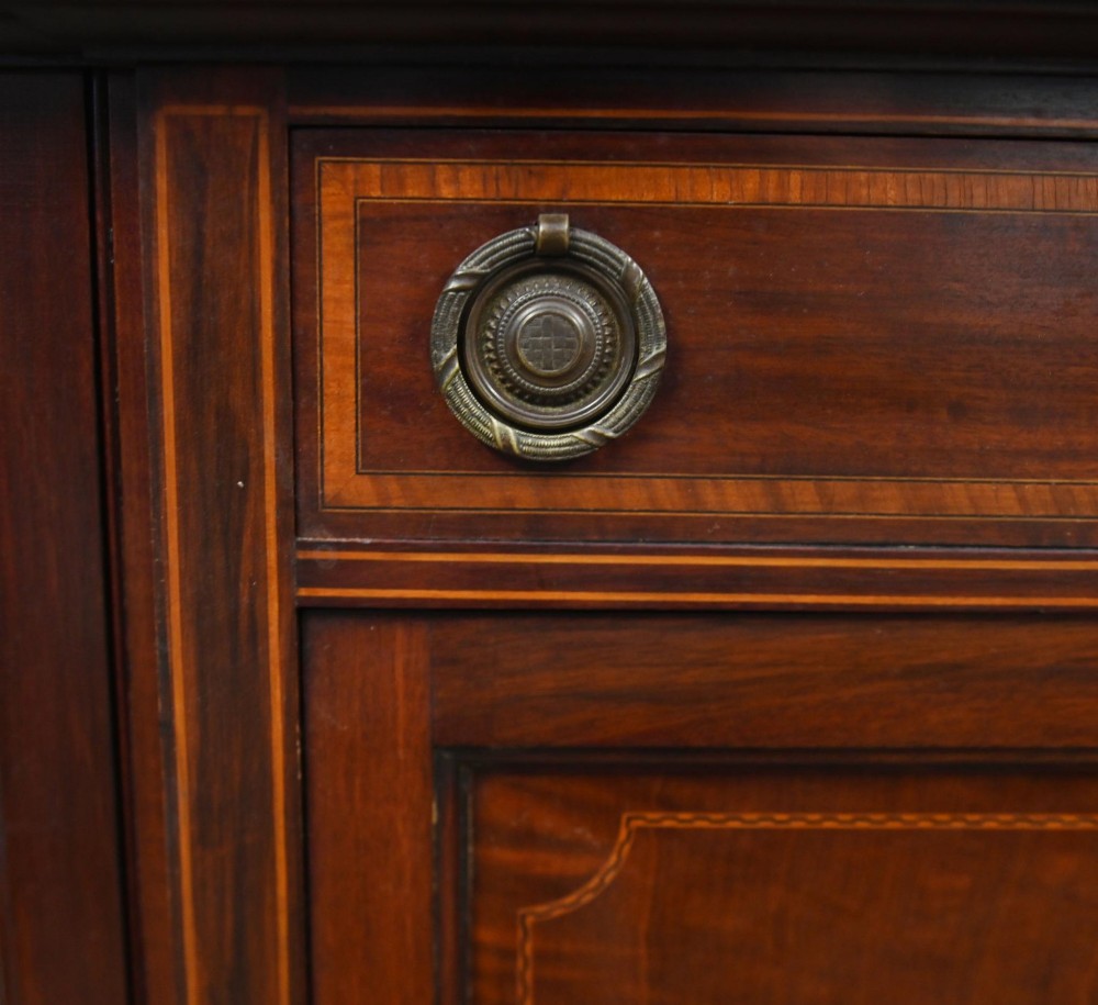 An Edwardian inlaid mahogany display cabinet featuring astragal glazed side doors, a central wooden cupboard with oval marquetry, and slender square tapered legs. View VII