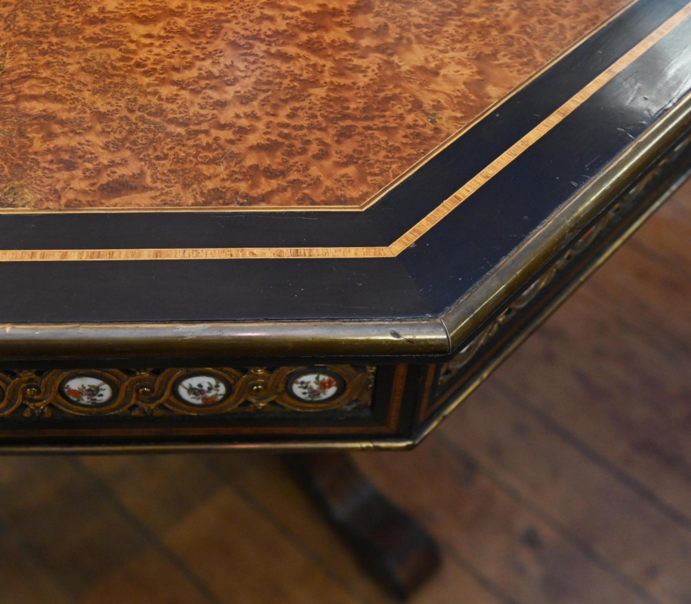 An octagonal Victorian centre table crafted from burr amboyna wood with ebonised borders and an apron decorated with porcelain roundels. View III