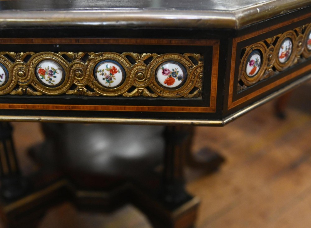 An octagonal Victorian centre table crafted from burr amboyna wood with ebonised borders and an apron decorated with porcelain roundels. View VII