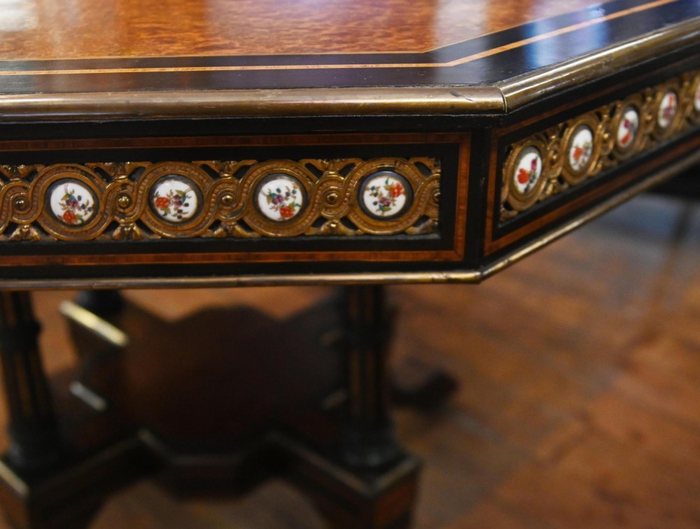 An octagonal Victorian centre table crafted from burr amboyna wood with ebonised borders and an apron decorated with porcelain roundels. View VIII