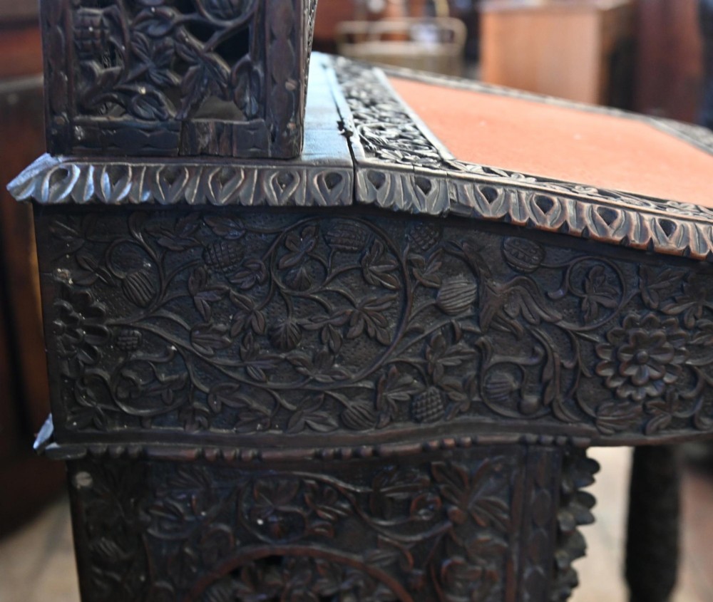 A dark hardwood Burmese Davenport desk with pierced carved floral decoration, an openwork gallery, and a terracotta leather writing surface. View III