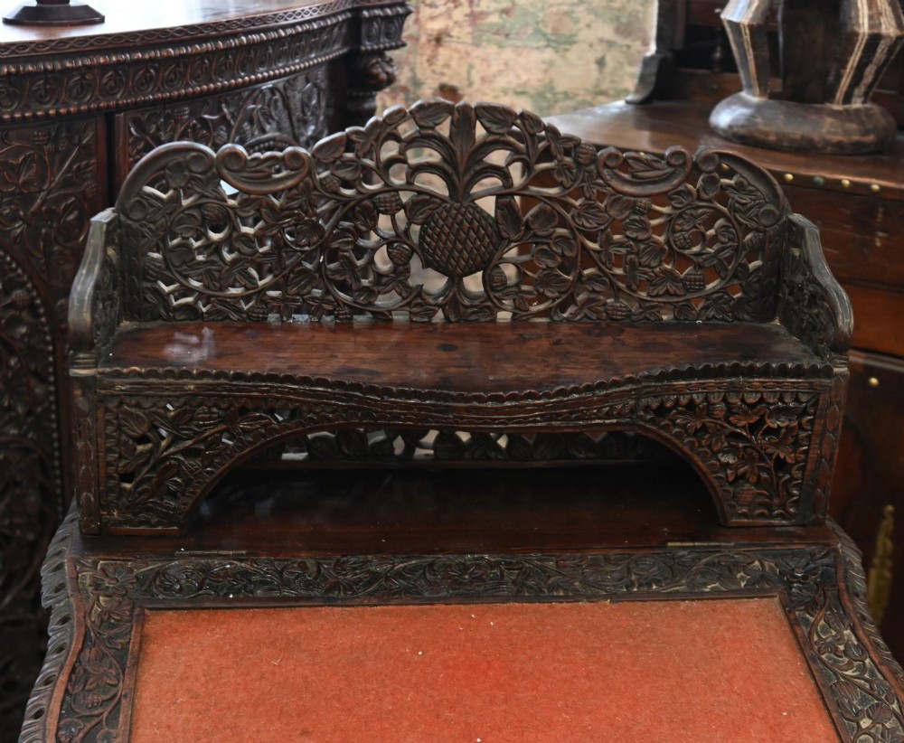 A dark hardwood Burmese Davenport desk with pierced carved floral decoration, an openwork gallery, and a terracotta leather writing surface. View VII