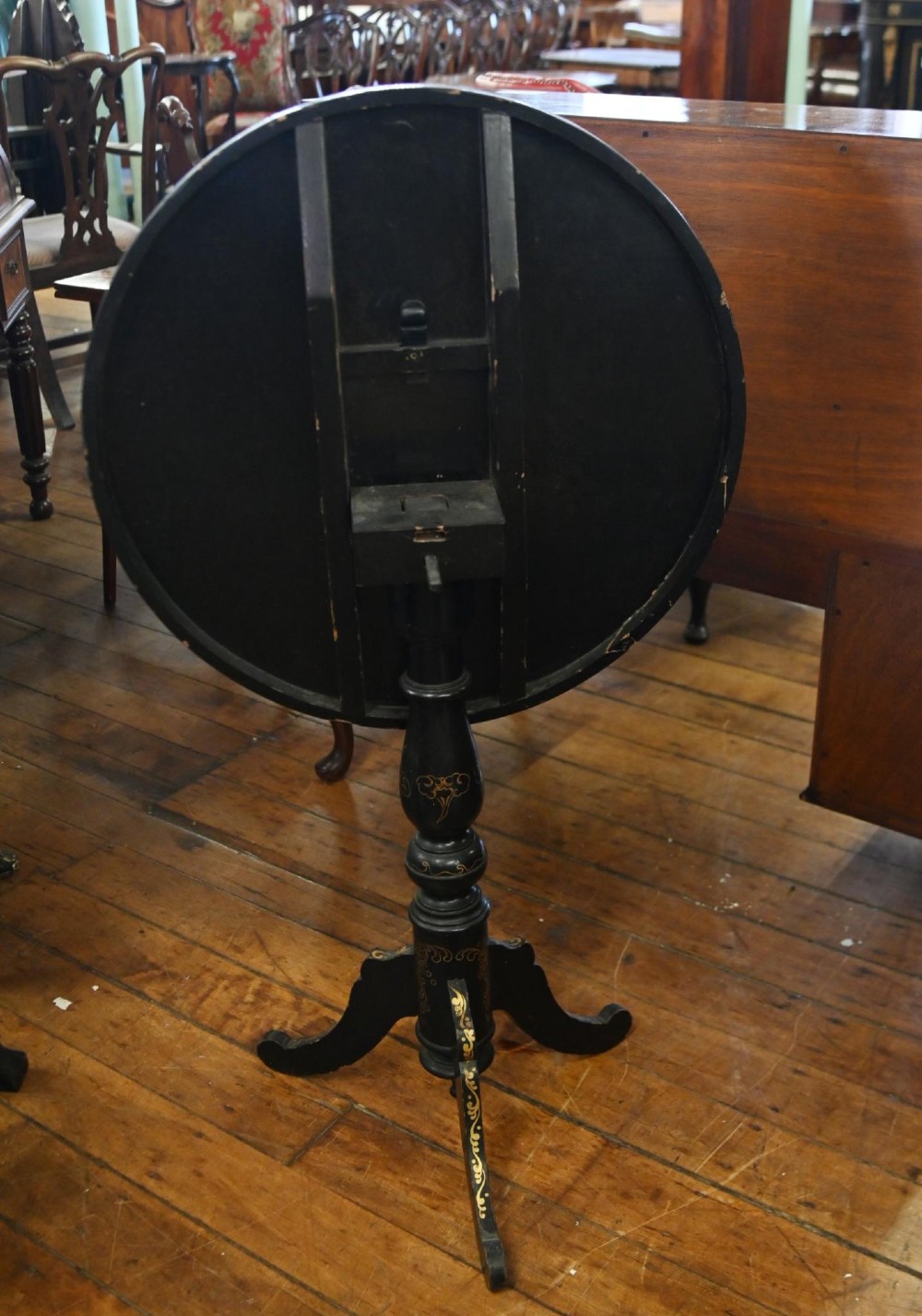 A black lacquered circular tilt-top side table featuring a gilt dragon motif, supported on a turned central column and tripod pedestal legs. View II