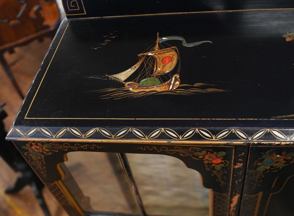 A black lacquered antique display cabinet featuring hand-painted gilded Chinoiserie scenes, two glazed side doors, and cabriole legs. View VI