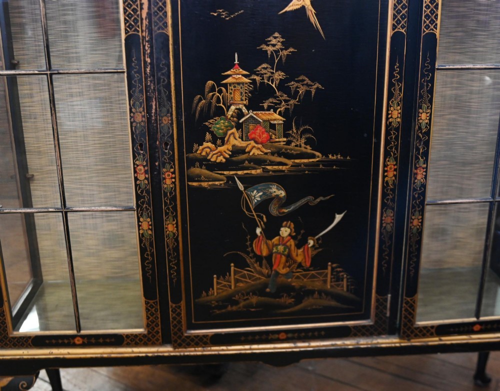 A black lacquered antique display cabinet featuring hand-painted gilded Chinoiserie scenes, two glazed side doors, and cabriole legs. View VII