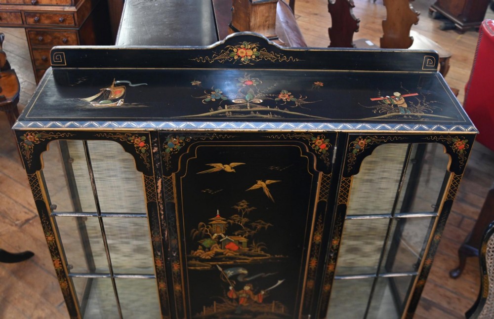 A black lacquered antique display cabinet featuring hand-painted gilded Chinoiserie scenes, two glazed side doors, and cabriole legs. View VIII