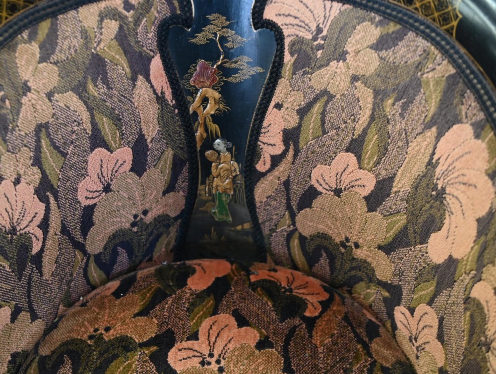 A pair of black lacquered Chinoiserie armchairs featuring hand-painted gold detail, curved backs, pink floral upholstery, and cabriole legs. View IV