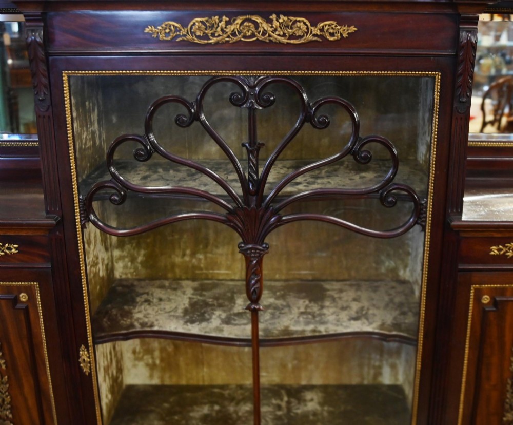 A dark mahogany display cabinet featuring gilt ormolu mounts, bevelled mirror panels, and a central glass door with decorative organic glazing bars. View V