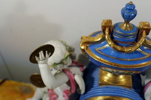 fig 1. An antique French Sevres-style porcelain mantel clock featuring cobalt blue glaze, hand-painted floral panels, gilt bronze mounts, and two sculpted cherub figures flanking the dial.