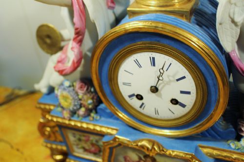 fig 2. An antique French Sevres-style porcelain mantel clock featuring cobalt blue glaze, hand-painted floral panels, gilt bronze mounts, and two sculpted cherub figures flanking the dial.