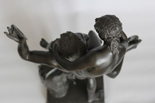 fig 2. A dark patinated bronze sculpture depicting a male faun holding cymbals with the infant Bacchus seated on his shoulders, mounted on a rectangular plinth base.