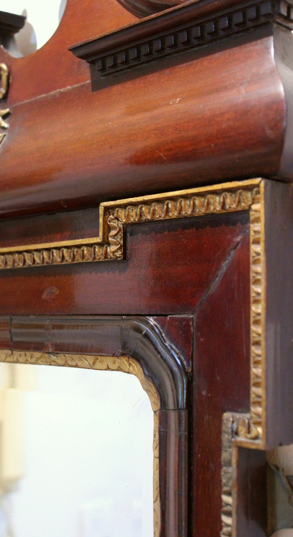 A tall rectangular Georgian mahogany wall mirror featuring a swan-neck pediment with a central urn finial, carved gilt accents, and a scrolled apron base. View II