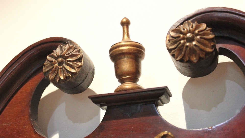 A tall rectangular Georgian mahogany wall mirror featuring a swan-neck pediment with a central urn finial, carved gilt accents, and a scrolled apron base. View IV