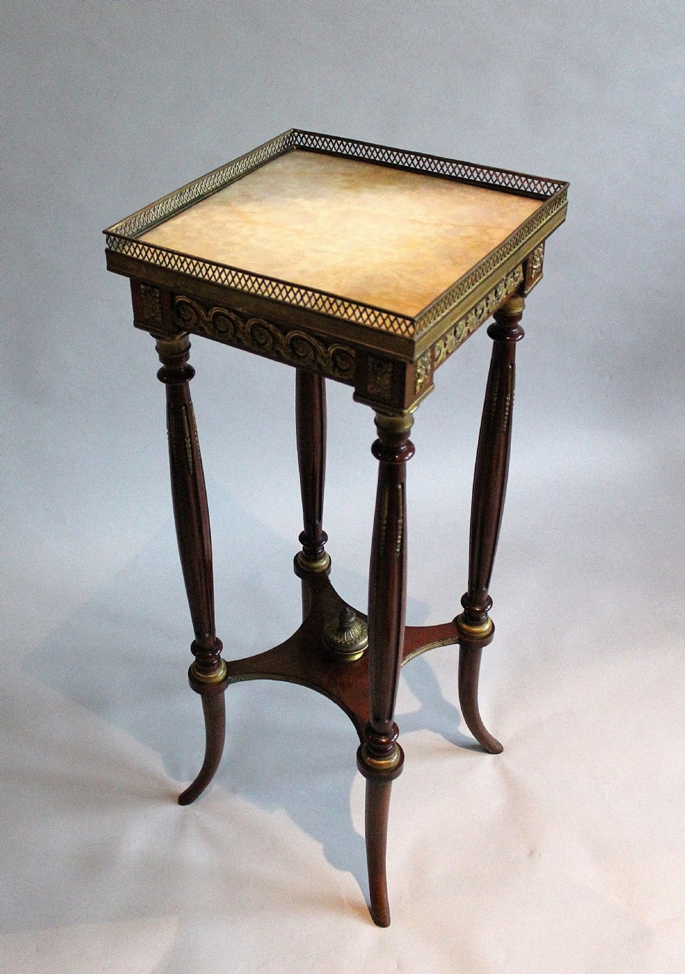 A tall, slender dark mahogany French occasional table featuring a pierced brass gallery top, fluted legs, and a low curved x-stretcher with a brass finial. View III