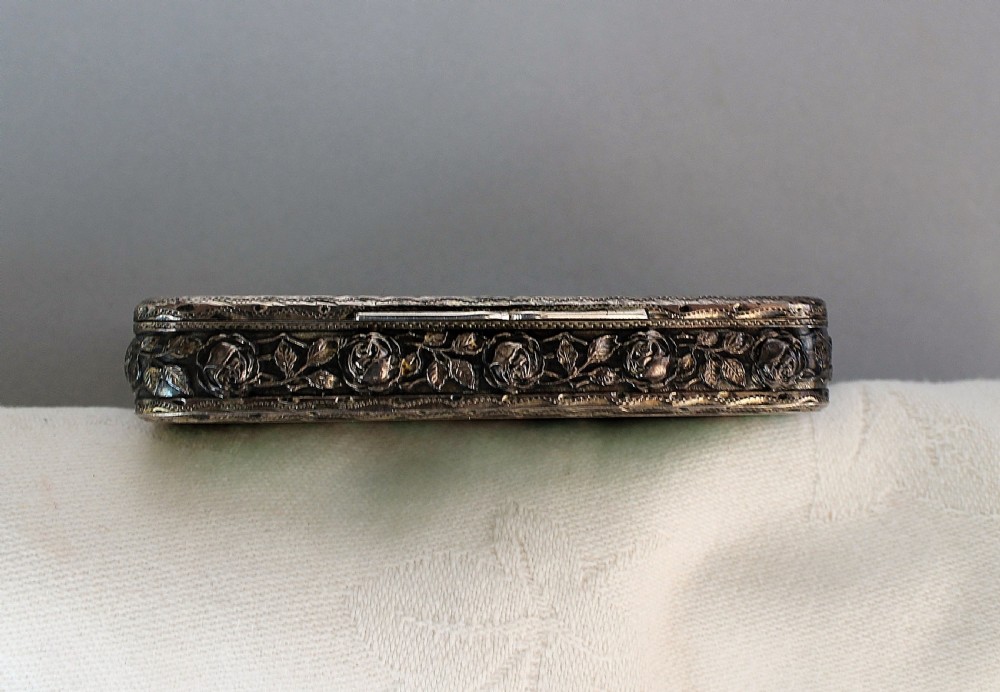 A small rectangular silver box featuring ornate foliate scrollwork overlaid upon a vibrant green engine-turned enamel surface. View III