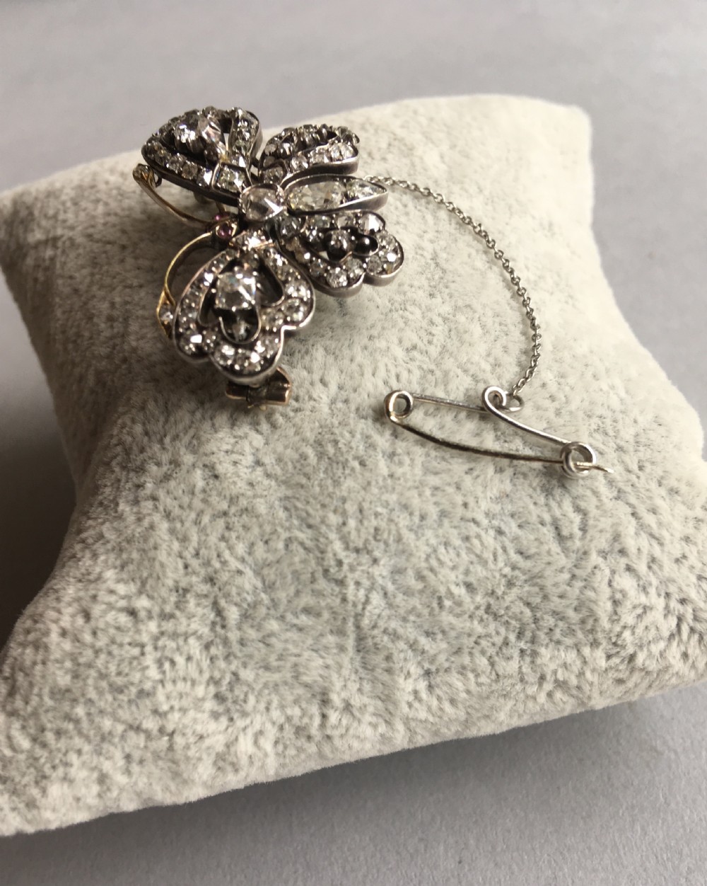 An antique diamond-encrusted brooch shaped like a butterfly with openwork wings, gold antennae, and an attached safety chain. View II