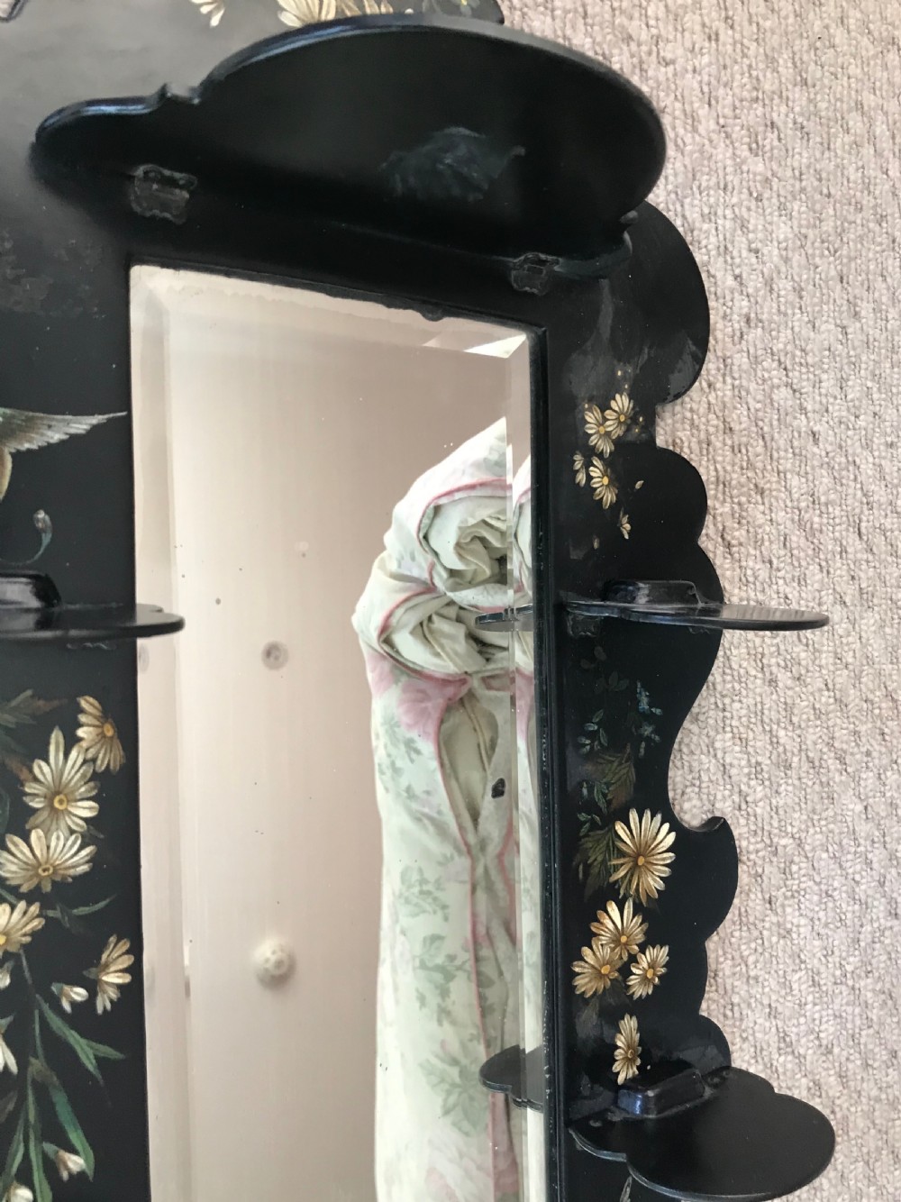 A Victorian ebonised wooden wall mirror featuring small tier display shelves and hand-painted white floral and bird motifs around a central rectangular mirror plate. View III
