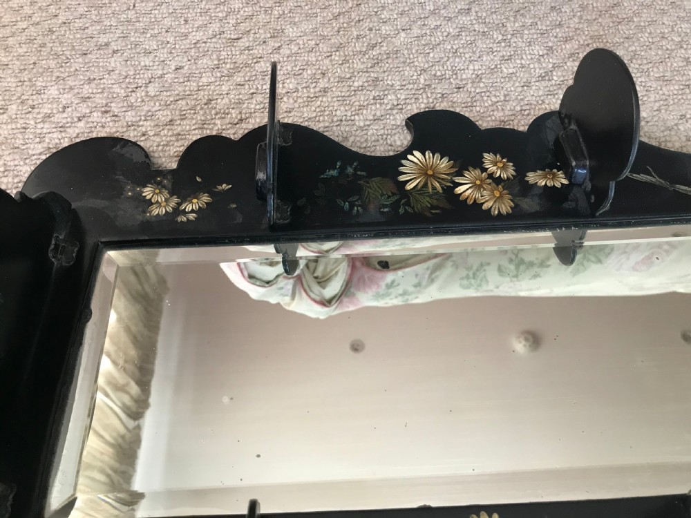 A Victorian ebonised wooden wall mirror featuring small tier display shelves and hand-painted white floral and bird motifs around a central rectangular mirror plate. View IV